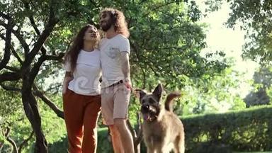 一对年轻漂亮的情侣和他们的狗在公园散步